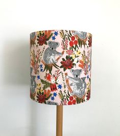 a lampshade with koalas and flowers on it is against a white wall