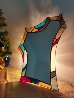 a stained glass mirror sitting on top of a wooden table next to a christmas tree