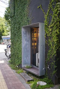 an outhouse that is covered in vines and has a door open to the outside