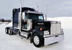 a black semi truck parked in the snow