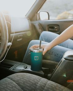 a person holding a cup in the back seat of a car