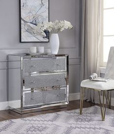 a mirrored cabinet with two drawers and flowers in the vase next to it on top of a rug