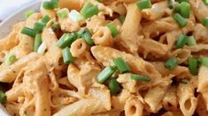 a white bowl filled with pasta and green onions