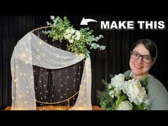 a woman is holding flowers in front of a wedding arch with the words make this