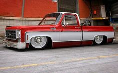 an old red and silver truck parked in front of a building