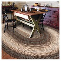 a table with two chairs and a rug on the floor in front of an old dresser