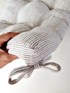 a hand holding a pillow with a knot on it