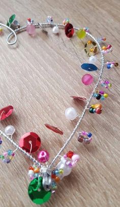 a bracelet with lots of colorful beads and charms hanging from it's side on a table