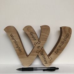 two wooden letters with writing on them sitting next to a black pen and white wall