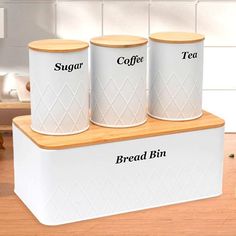 three white canisters with the words coffee, bread and tea on them sitting on a counter