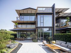 an outdoor patio with couches and tables in front of a large building that has many windows