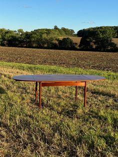 a wooden table sitting on top of a lush green field