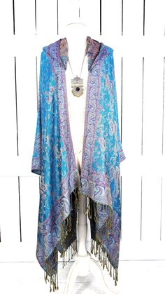 Hooded blue purple paisley pashmina kimono cover up jacket with custom length and fringe detail Measurements...taken flat - width across seam to seam: 46"  - length with 4" fringe: 38" (in photo) Features... - lovely soft woven medium weigh pashmina fabric - bohemian oversized flowing design - cardigan style with an open front and generous arm holes  - attached hood - universal design allows a comfortable fit for small through plus sizes -customize your length and fringe detail - the perfect layering piece that can easily be dressed up or down - wrinkle resistant  - handmade with love by me in California Blue Spring Outerwear With Tassels, Spring Blue Outerwear With Tassels, Blue Outerwear With Tassels For Spring, Blue Long Sleeve Outerwear With Tassels, Blue Tasseled Outerwear For Fall, Bohemian Blue Cape Outerwear, Bohemian Blue Cape-style Outerwear, Spring Shawl With Tassels, Fitted Bohemian Outerwear With Tassels