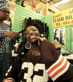 a woman is getting her hair done by another woman in the background at a salon