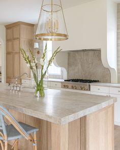 a large kitchen with an island in the middle and two blue chairs at the end