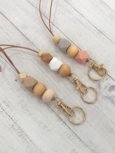 three wooden beaded keychains hanging from leather cord on white wood flooring