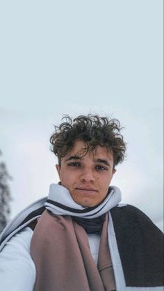 a young man with curly hair wearing a scarf