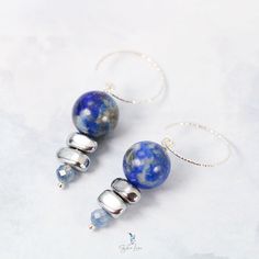 These elegant Lapis Lazuli bead stones dangle drop earrings feature a beautiful deep blue 12 mm Lapis Lazuli beads dangle drop and two painted silver Hematite stone beads, a faceted blue Kyanite tiny bead drop at the end. The beads are on solid 925 sterling silver eye pin, hooked on a diamond cut texture 925 sterling silver ear wire. Add these elegant Lapis Lazuli, Hematite and Kyanite beads dangle drop earrings to your everyday fine jewelry collection or as a gift for your loved one. Materials: 925 sterling silver, Lapis Lazuli, UV hematite, kyaniteDimensions: 1.84 x 0.46 in Jewelry Care: See more information about how to care for your jewelry here. Shipping Policy: Orders will be shipped within 1-3 business days. Economy shipping will take 7-14 days to arrive and standard shipping is 1- Round Beads Earrings With Natural Stones For Jewelry Making, Round Beads Earrings For Jewelry Making, Elegant Blue Faceted Beads Earrings, Elegant Gemstone Beaded Earrings For Gift, Agate Earrings With Natural Stones In Round Beads Shape, Metal Beaded Earrings With Faceted Beads For Gifts, Silver Jewelry With Faceted Beads Made Of Lapis Lazuli, Silver Beaded Earrings With Natural Stones, Elegant Adjustable Beaded Earrings With Gemstone Beads