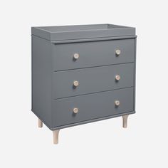 a grey dresser with three drawers and two knobs on each drawer, in front of a white background