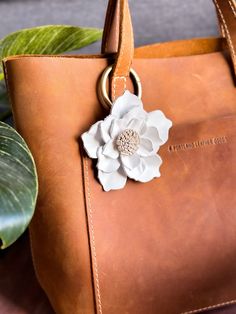 a brown leather bag with a white flower on it