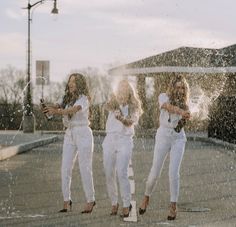 three women standing in the rain holding umbrellas