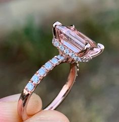 a close up of a person's hand holding an engagement ring