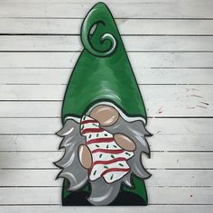 a green gnome's hat with red and white stripes on it is hanging from the side of a wooden wall