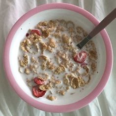 a bowl of cereal with strawberries and milk