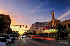 a city street with cars driving down it at sunset