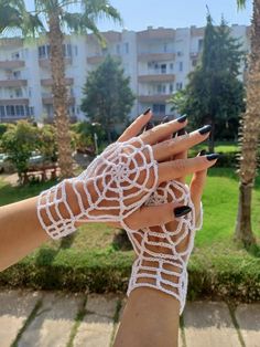 a woman's hand with black and white nail polish holding up an intricate lace design on her wrist