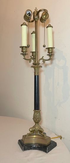 an antique brass candelabra with three candles on it, sitting on a table