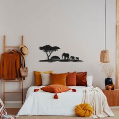 a bedroom with an elephant wall decal on the wall and orange pillows in front of it