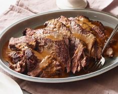 a plate full of meat and gravy on top of a table with utensils