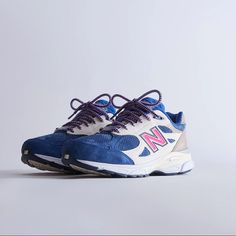 a pair of new balance shoes with purple laces on the top and white soles