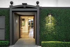 an entrance to a house with green plants on the wall and door way leading into it