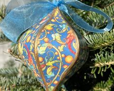 an ornament hanging from the top of a christmas tree with a blue ribbon