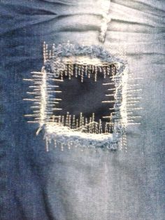 the back pocket of someone's jeans with pins sticking out of it and holes in them