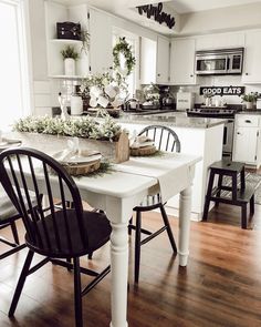 a white kitchen with black chairs and an island in front of the stove top oven