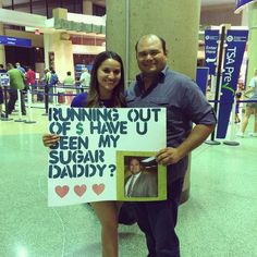 a man standing next to a woman holding a sign