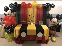 mickey and minnie mouse balloons are on display at a birthday party in front of a table