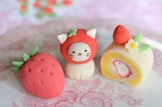 three small toy animals sitting on top of a plate next to a strawberry and roll