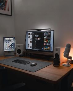 two computer monitors sitting on top of a wooden desk next to speakers and a keyboard