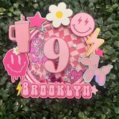 a pink and white birthday sign sitting on top of a lush green field with flowers