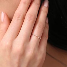 a close up of a person's hand with a ring on their finger and an object in the background