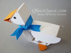 an origami bird with a blue bow on its head in a white box