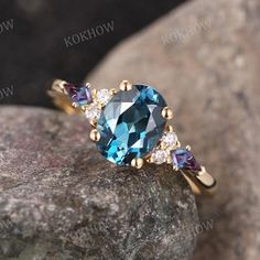 an oval blue topazte ring with three smaller stones on the side, sitting on a rock