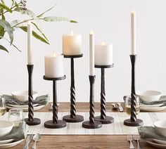 a table set with candles, plates and utensils on top of a wooden table