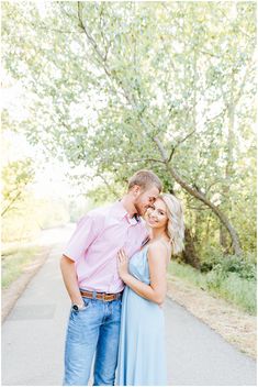 a man and woman standing next to each other in front of trees