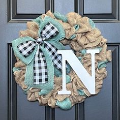 a wreath with the letter n on it hanging on a front door, decorated with burlap and gingham