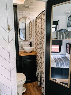 a bathroom with a toilet, sink and mirror in it's stall area next to a bed